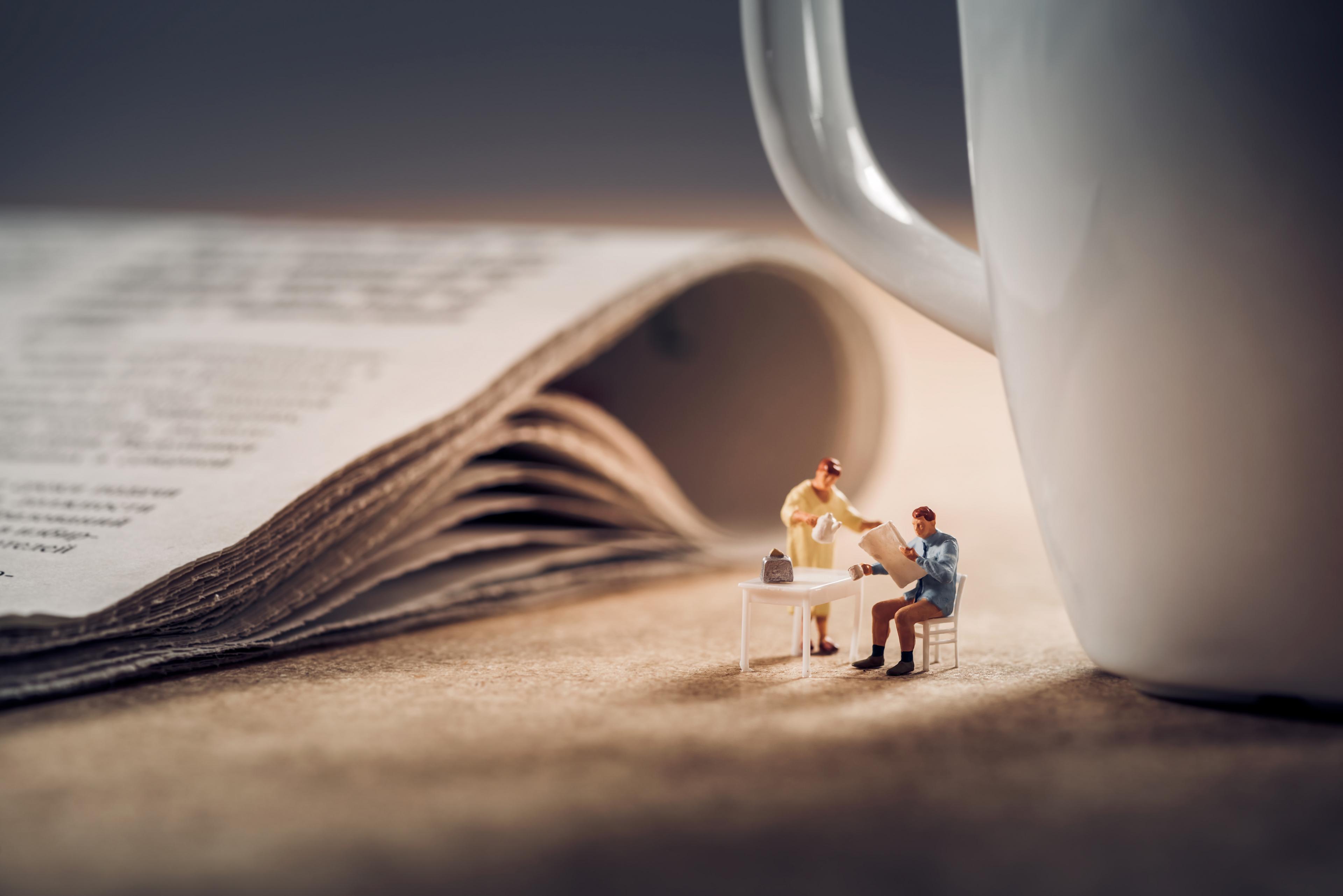 Kleine mensjes bij een krant en een kop koffie